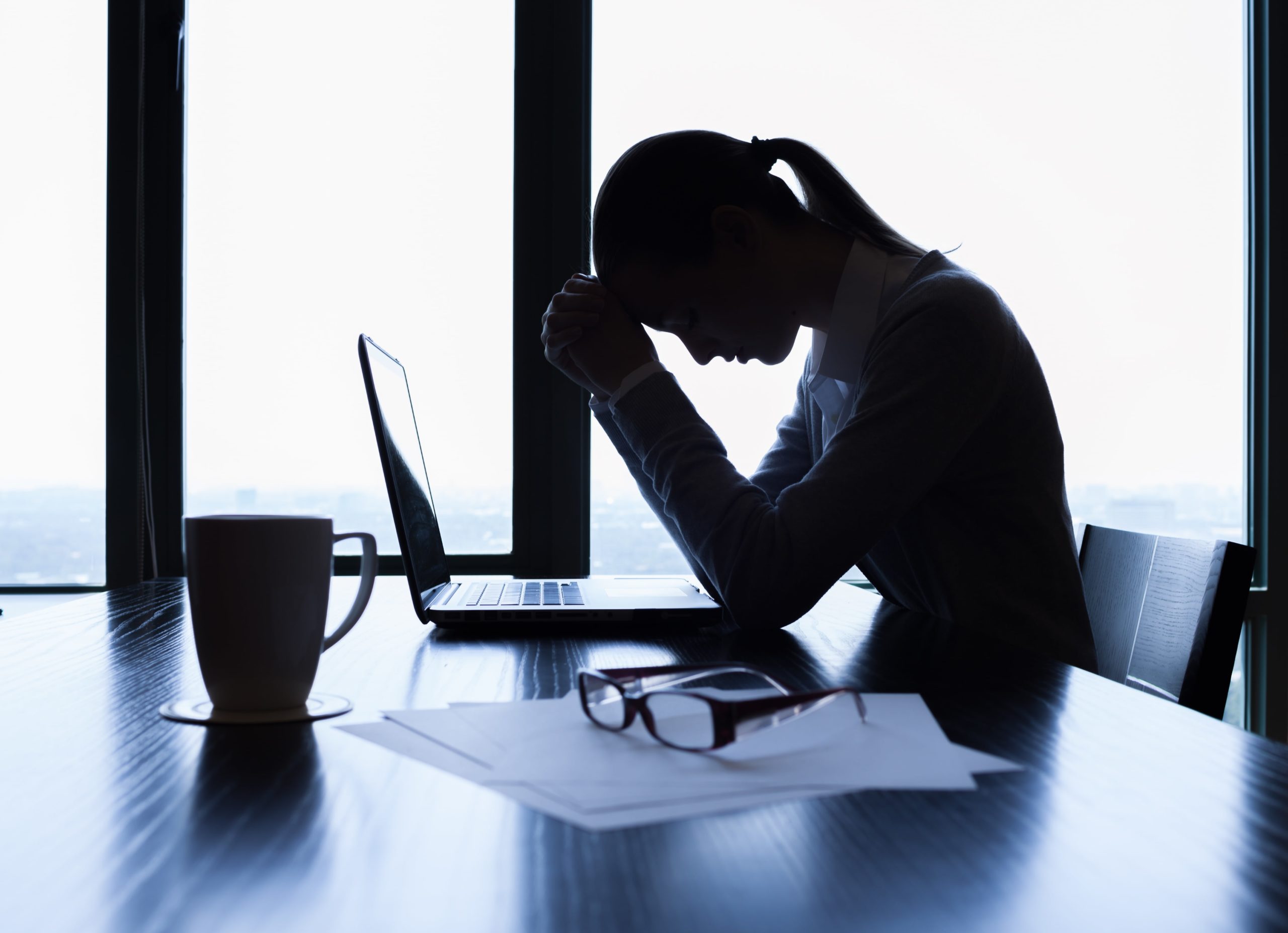 Woman on a computer experiencing headaches and fatigue, potential side effects of carbidopa levodopa